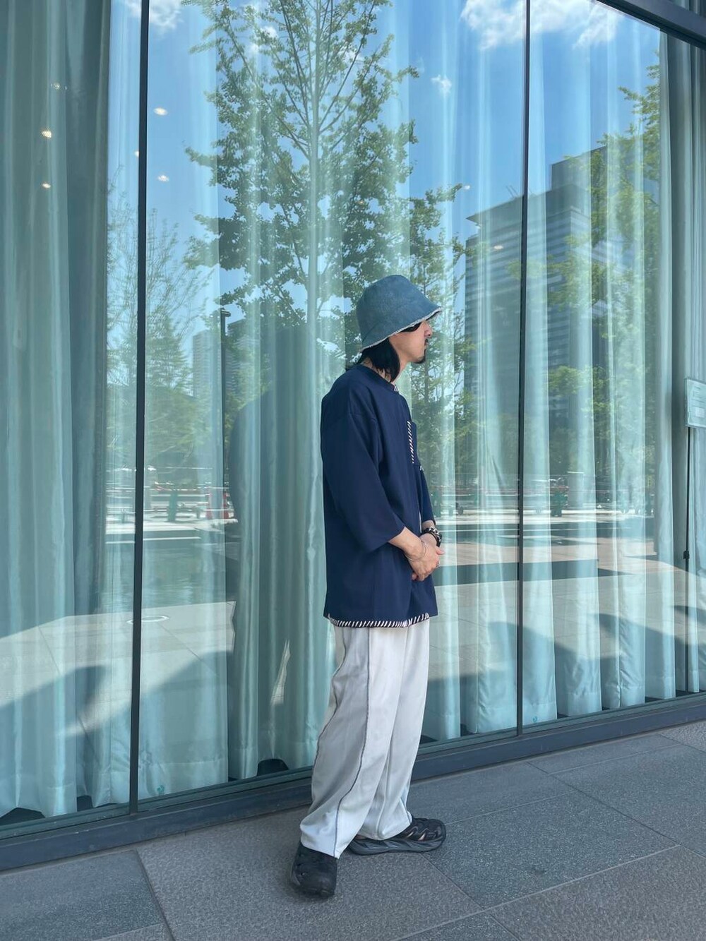 グレー系のその他パンツ、ブルー系のTシャツ/カットソー、ブルー系のハットを着用したメンズの夏コーディネートの4枚目の写真