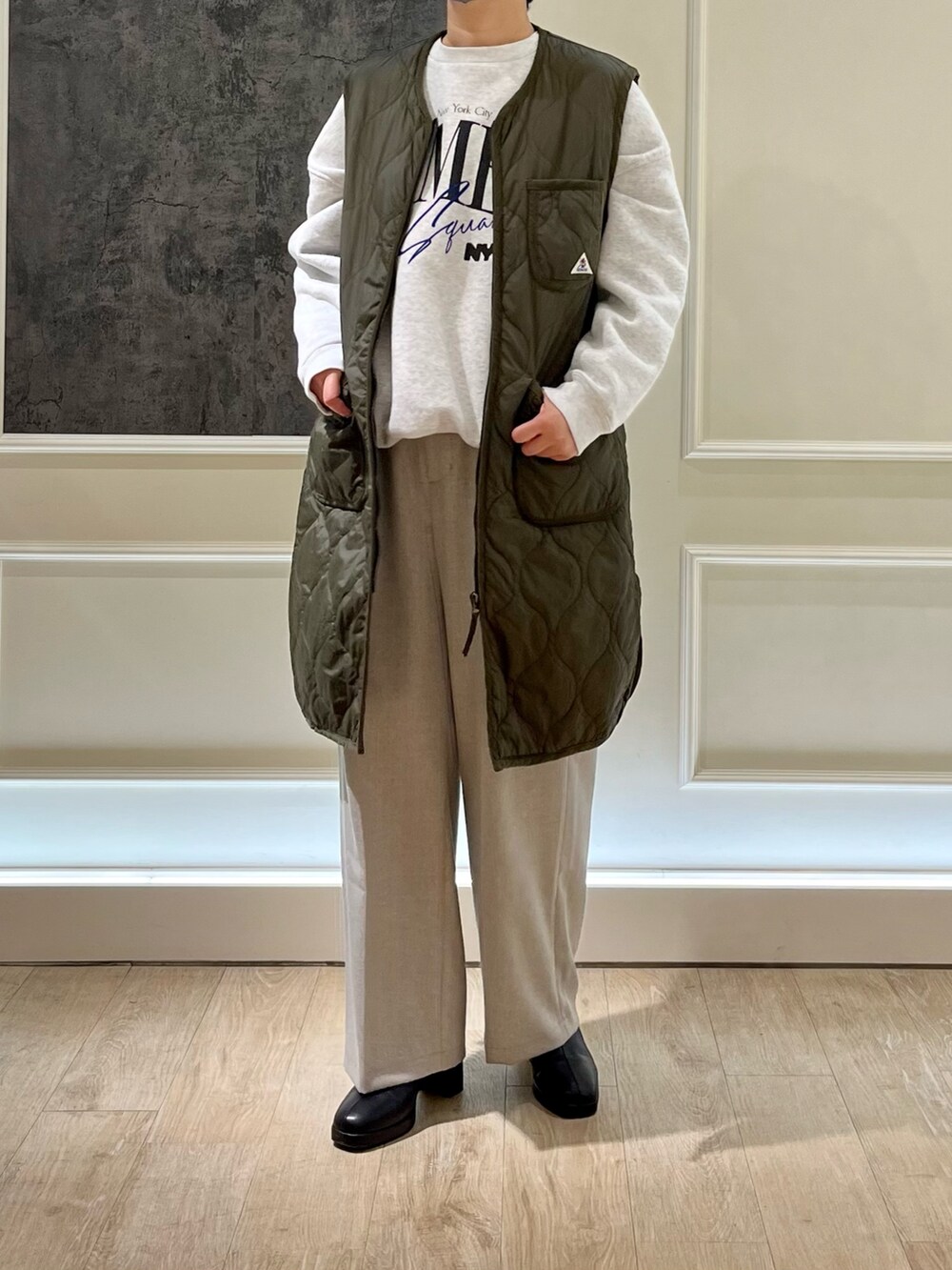 グリーン系のダウンベスト、グレー系のスウェット、ブラック系のブーツを着用したレディースの秋コーディネートの3枚目の写真