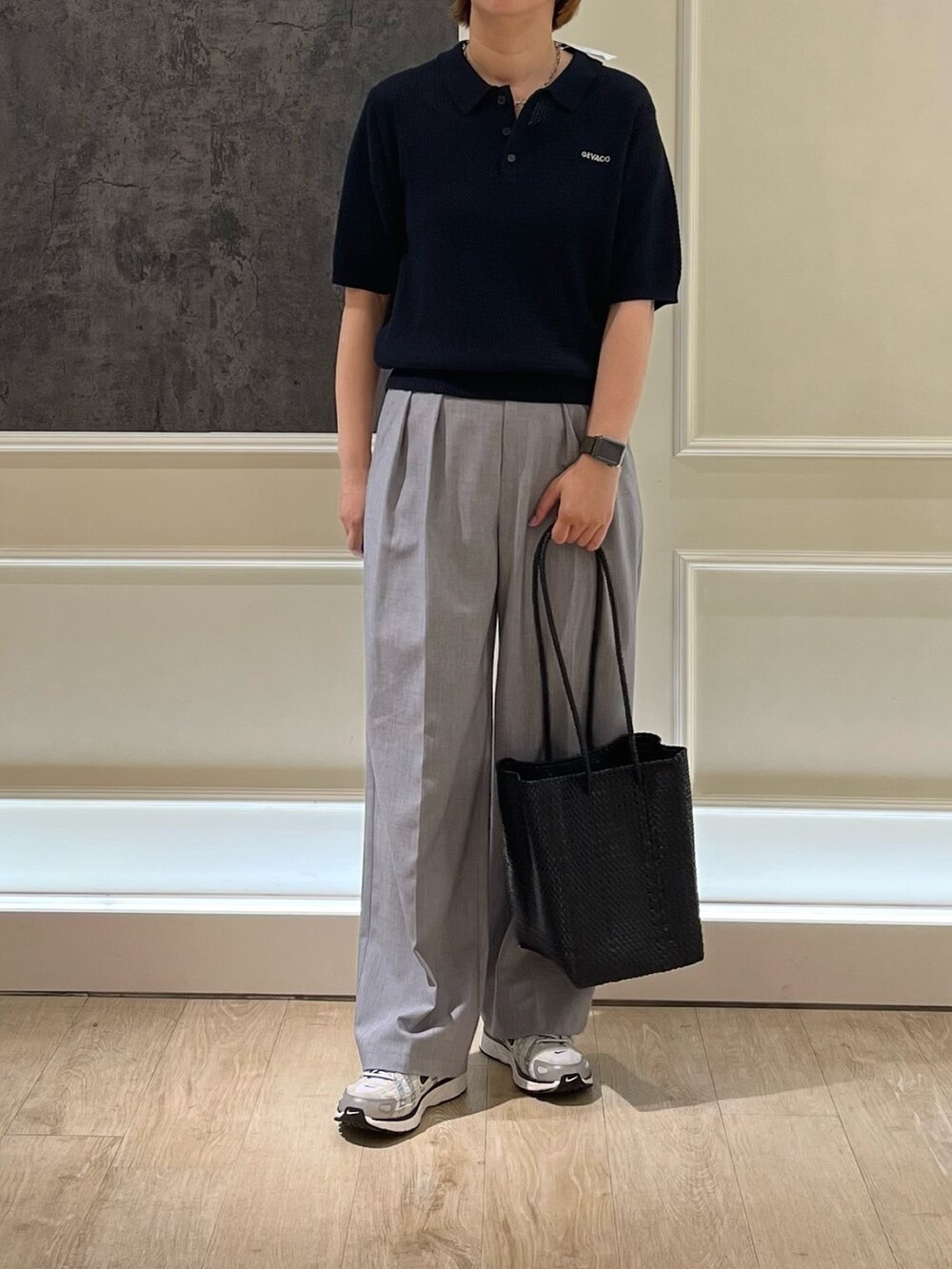 ブルー系のニット/セーター、ブラック系のかごバッグ、グレー系のスラックスを着用したレディースの春コーディネートの2枚目の写真