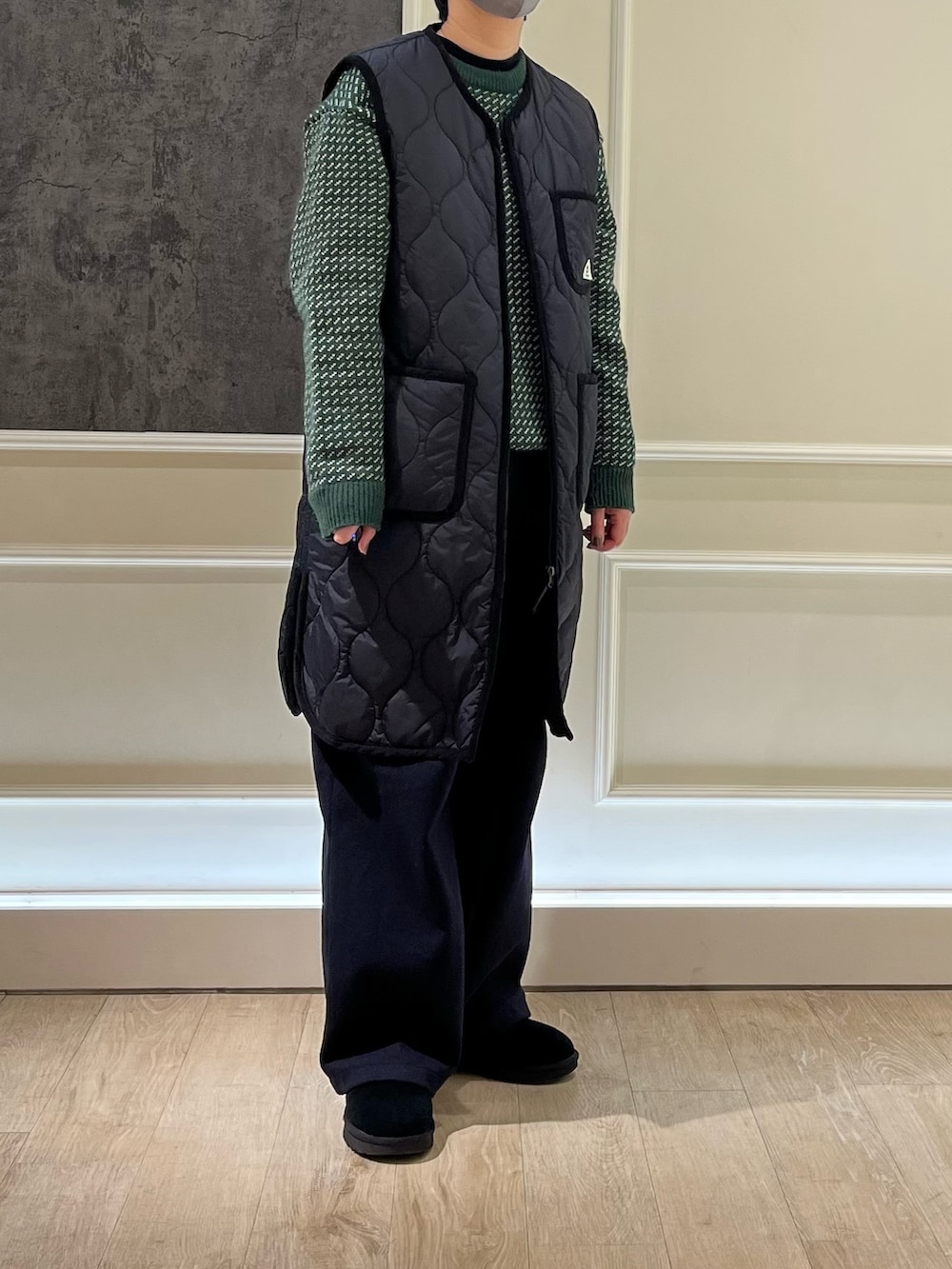 ブラック系のダウンベスト、グリーン系のニット/セーターを着用したレディースの冬コーディネートの2枚目の写真