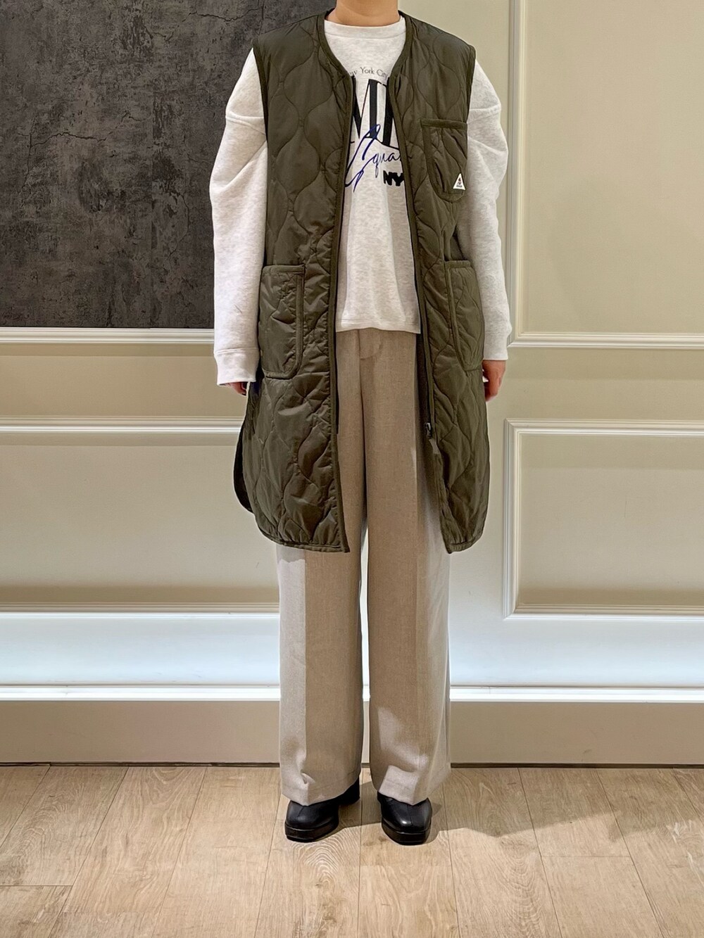 グリーン系のダウンベスト、グレー系のスウェット、ブラック系のブーツを着用したレディースの秋コーディネートの2枚目の写真