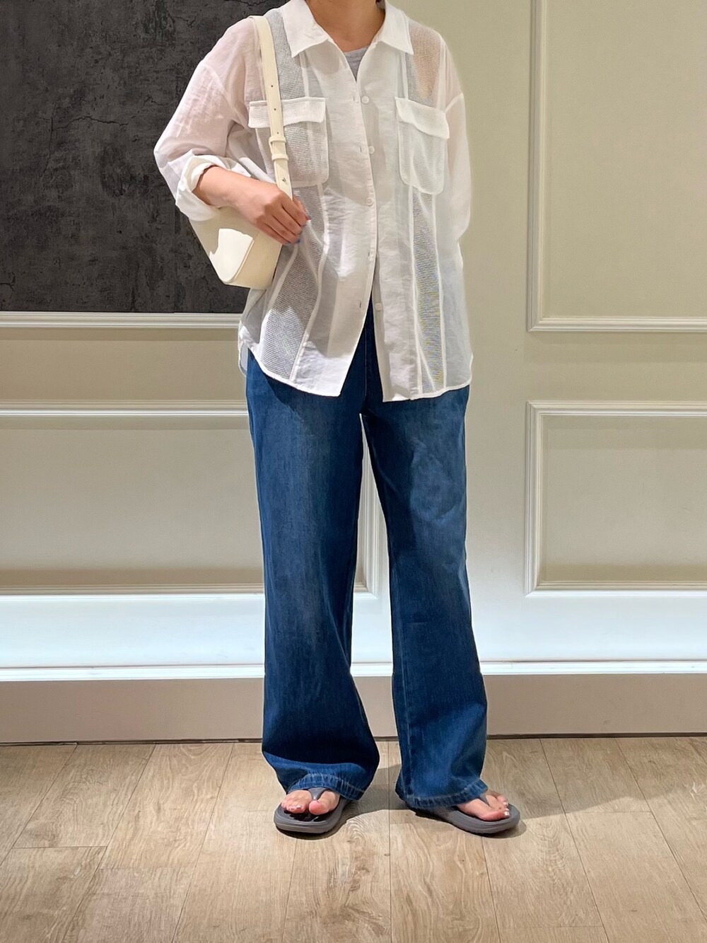 ブルー系のデニムパンツ、グレー系のサンダル、ホワイト系のハンドバッグを着用したレディースの夏コーディネートの3枚目の写真