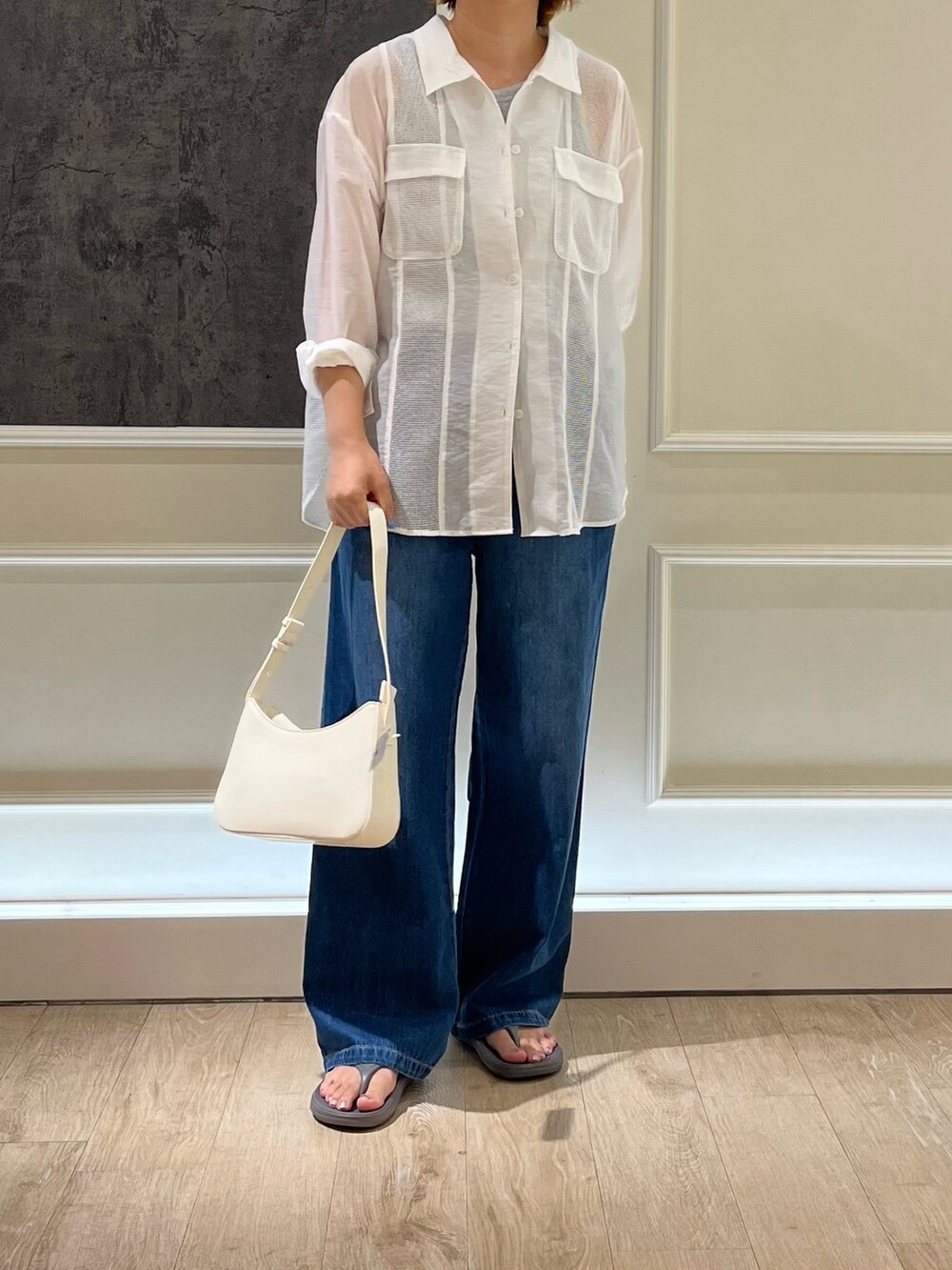 ブルー系のデニムパンツ、グレー系のサンダル、ホワイト系のハンドバッグを着用したレディースの夏コーディネートの2枚目の写真