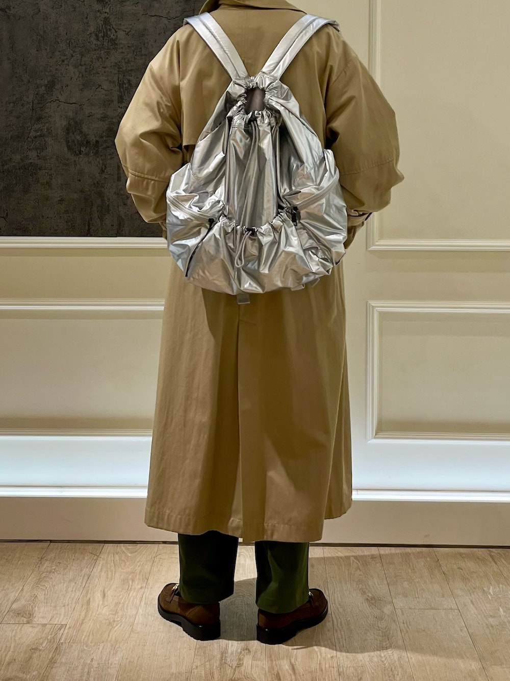 ベージュ系のトレンチコート、ブルー系のスウェット、シルバー系のバックパック/リュックを着用したレディースの冬コーディネートの3枚目の写真