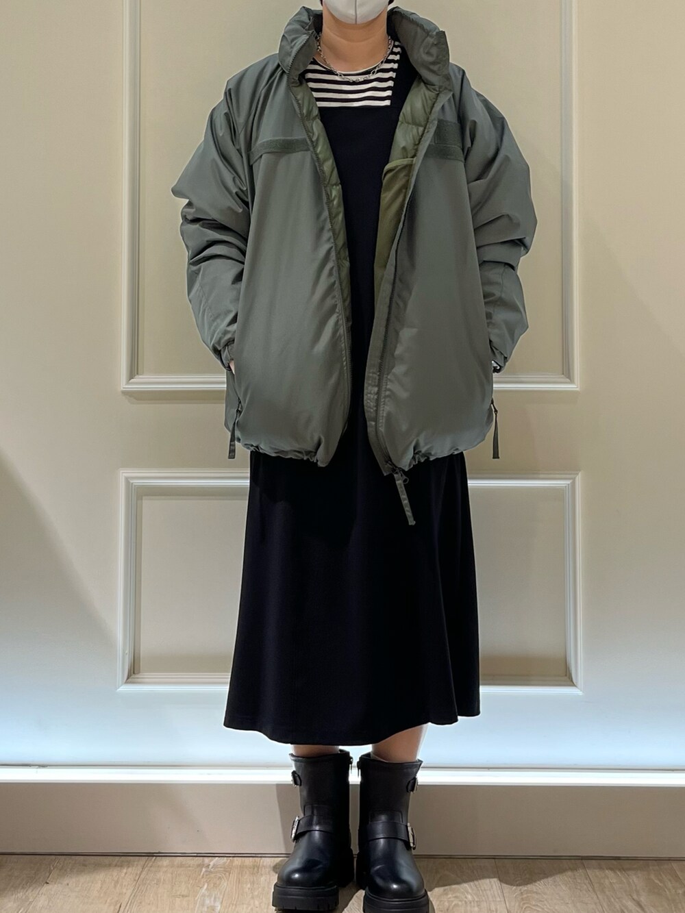 ブラック系のジャンパースカート、ブラック系のブーツ、グレー系のTシャツ/カットソーを着用したレディースの秋コーディネートの2枚目の写真