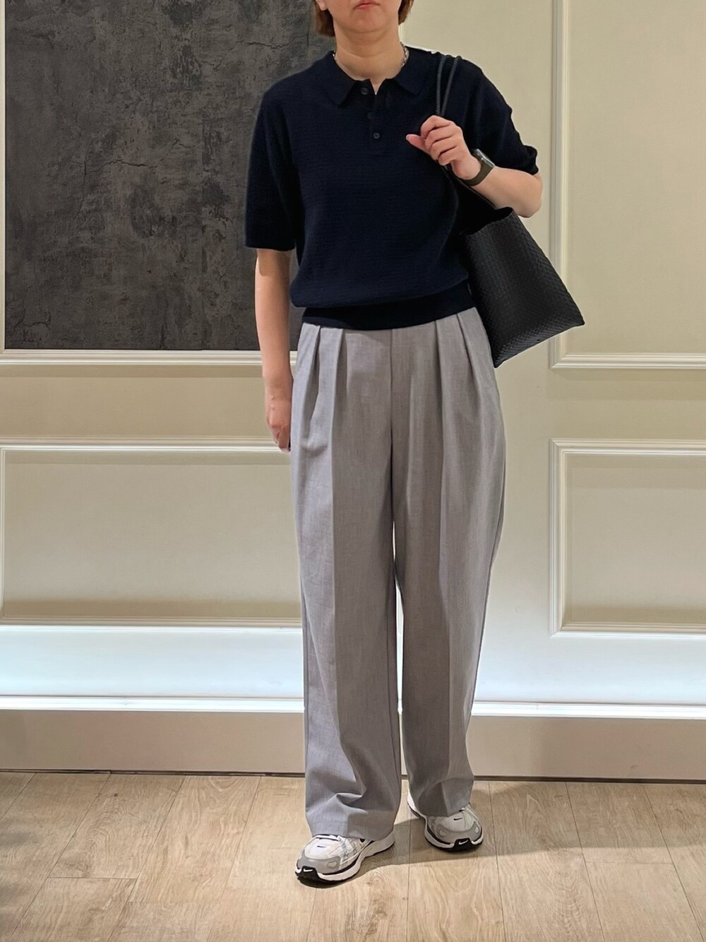 ブルー系のニット/セーター、ブラック系のかごバッグ、グレー系のスラックスを着用したレディースの春コーディネートの3枚目の写真