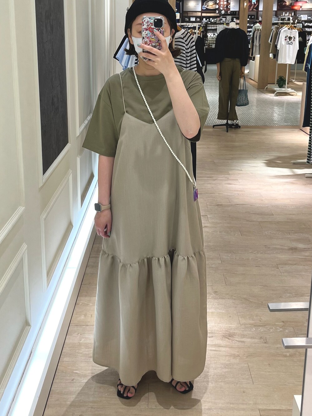 ベージュ系のワンピース、グリーン系のTシャツ/カットソー、ブラック系のサンダルを着用したレディースの春コーディネートの3枚目の写真