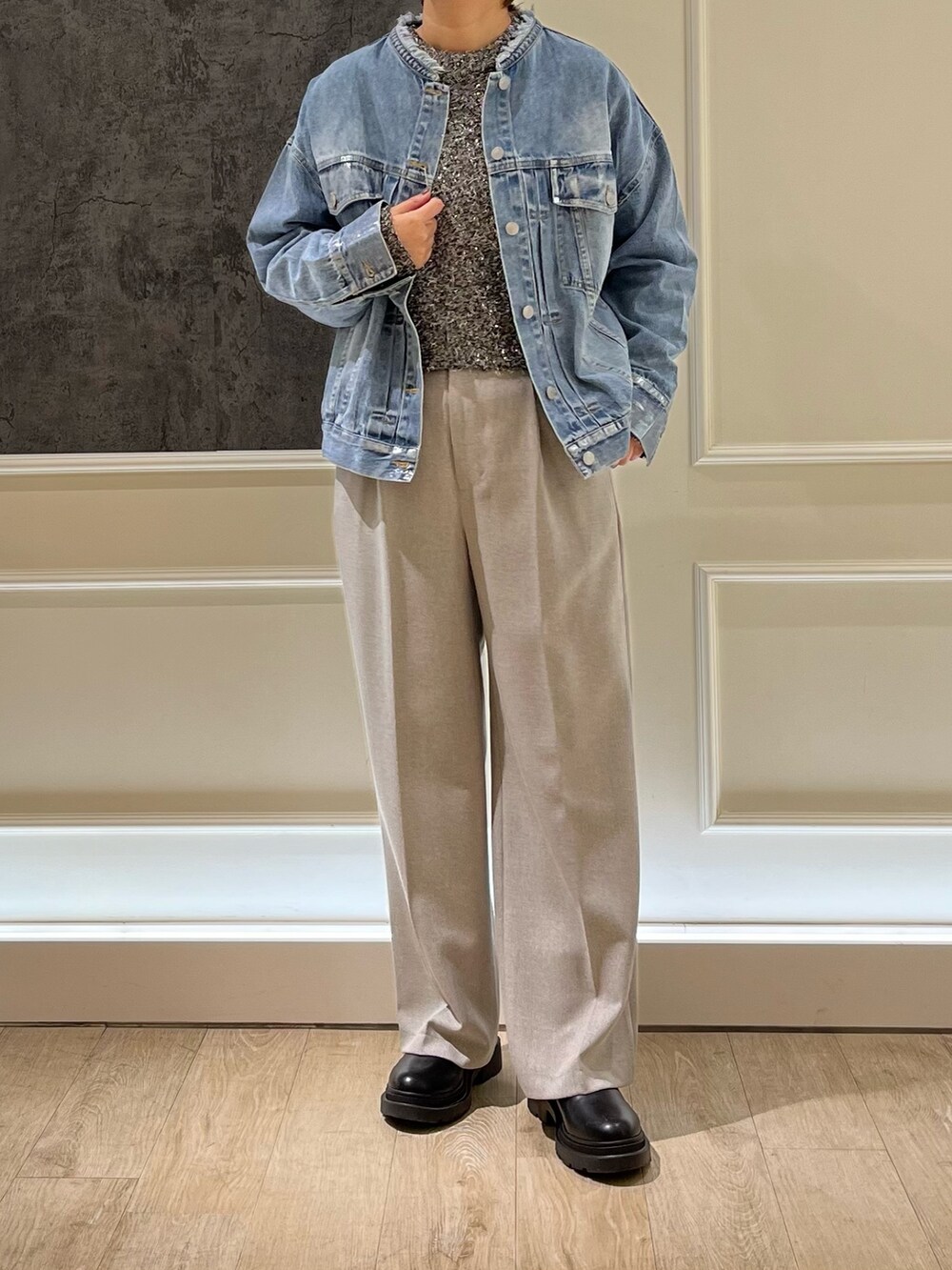 ベージュ系のスラックス、ブルー系のデニムジャケット、ブラック系のニット/セーターを着用したレディースの冬コーディネートの2枚目の写真