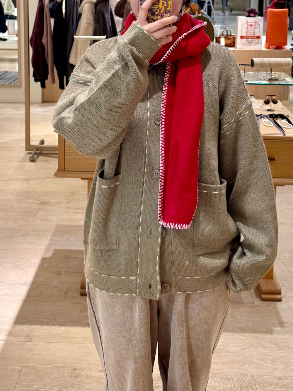 ベージュ系のカーディガン/ボレロ、ベージュ系のスウェットパンツ、レッド系のマフラーを着用したレディースの冬コーディネートの3枚目の写真