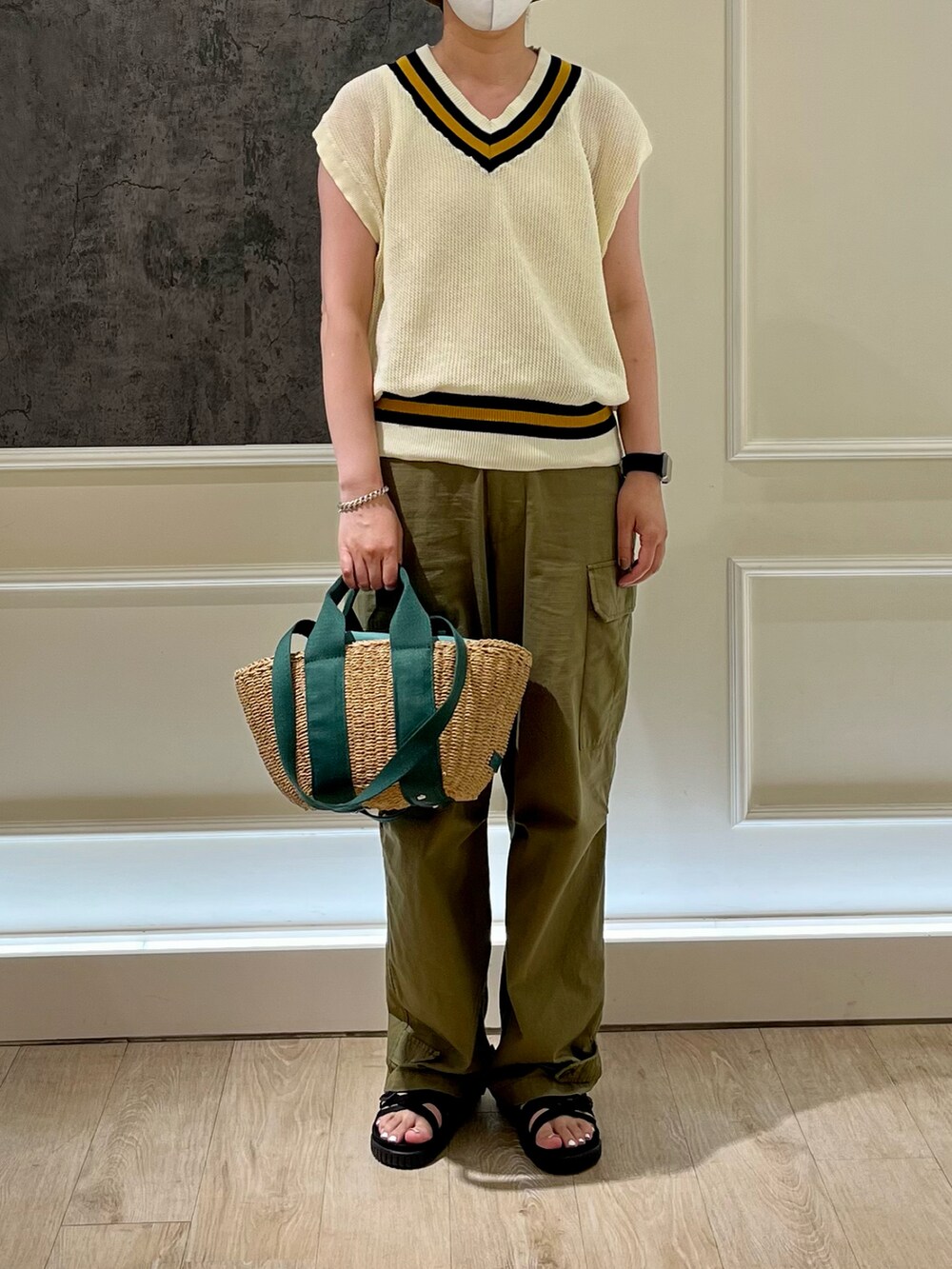 ホワイト系のベスト、ブルー系のかごバッグ、グリーン系のカーゴパンツを着用したレディースの夏コーディネートの3枚目の写真