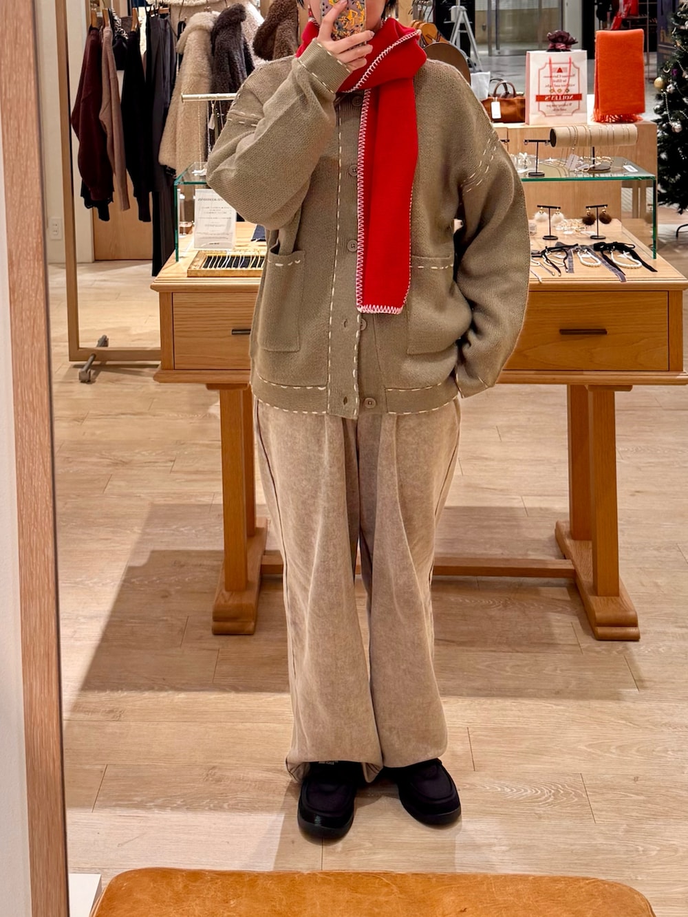 ベージュ系のカーディガン/ボレロ、ベージュ系のスウェットパンツ、レッド系のマフラーを着用したレディースの冬コーディネートの2枚目の写真