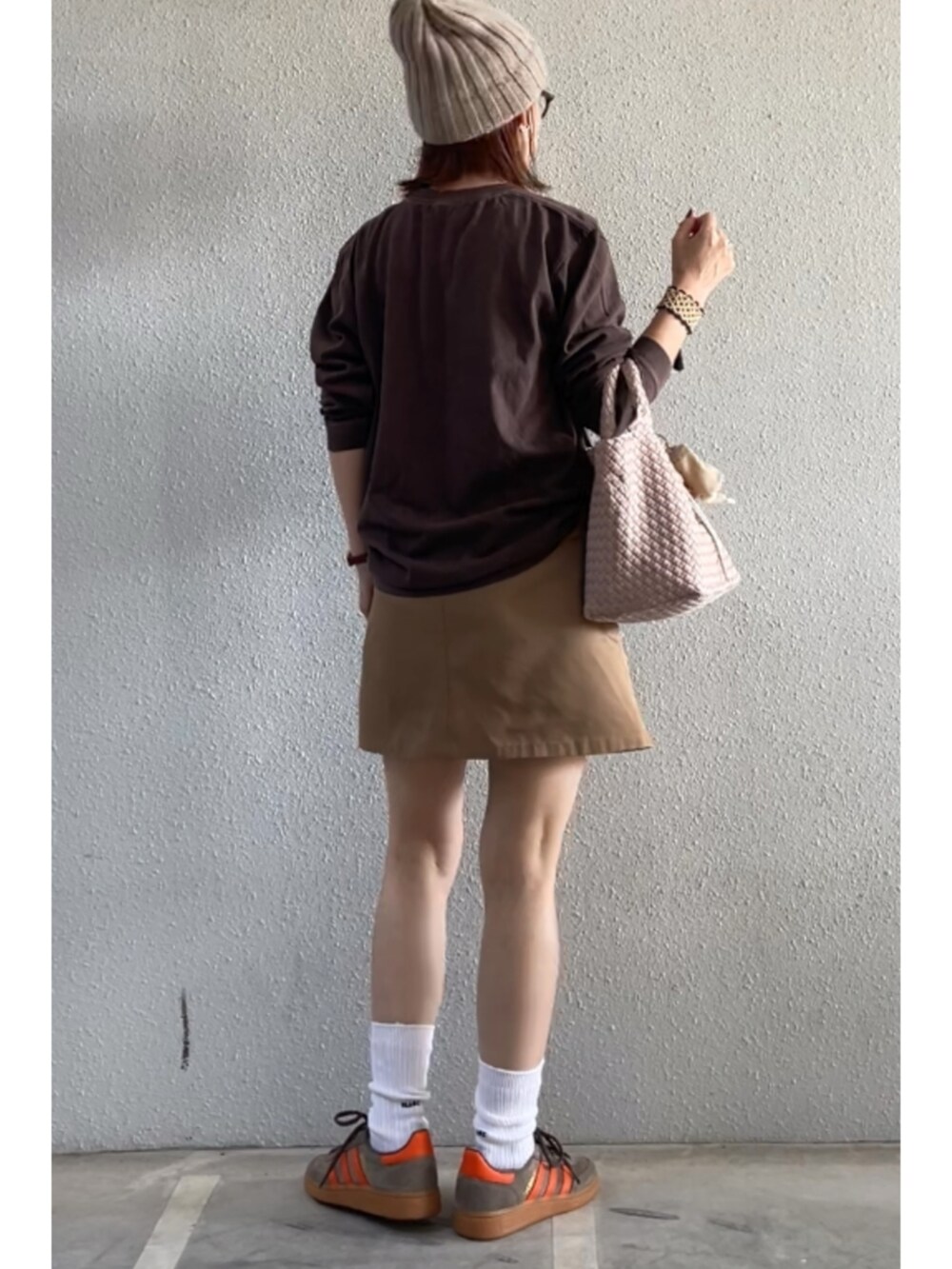 ブラウン系のTシャツ/カットソー、ベージュ系のスカート、ブラウン系のスニーカーを着用したレディースの秋コーディネートの2枚目の写真