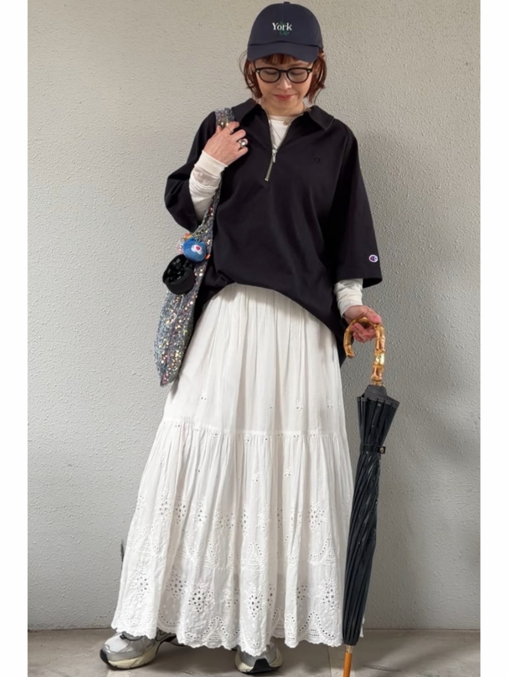 ブラック系のTシャツ/カットソー、ホワイト系のスカート、ホワイト系のスニーカーを着用したレディースの春コーディネートの2枚目の写真