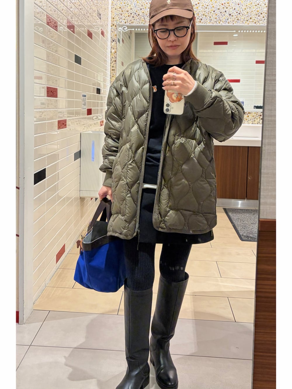 ブラック系のブーツ、ブルー系のトートバッグ、グリーン系のその他アウターを着用したレディースの冬コーディネートの2枚目の写真