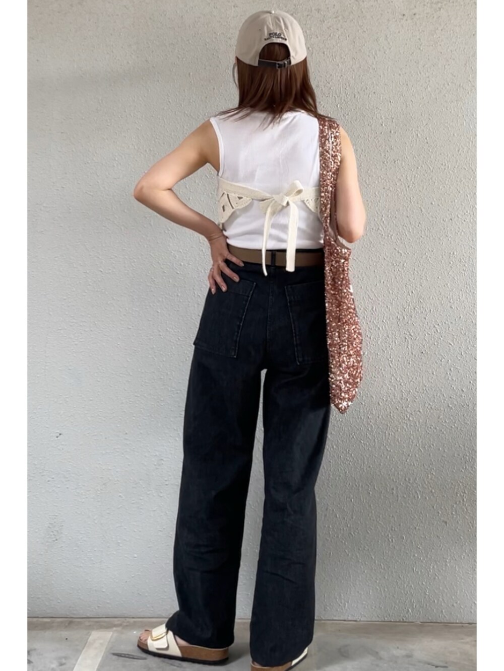 ブラック系のデニムパンツ、ホワイト系のサンダル、ピンク系のトートバッグを着用したレディースの夏コーディネートの2枚目の写真