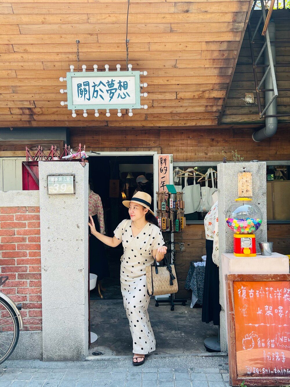 ブラック系のトートバッグ、ベージュ系のワンピース、オレンジ系のサンダルを着用したレディースの夏コーディネートの3枚目の写真