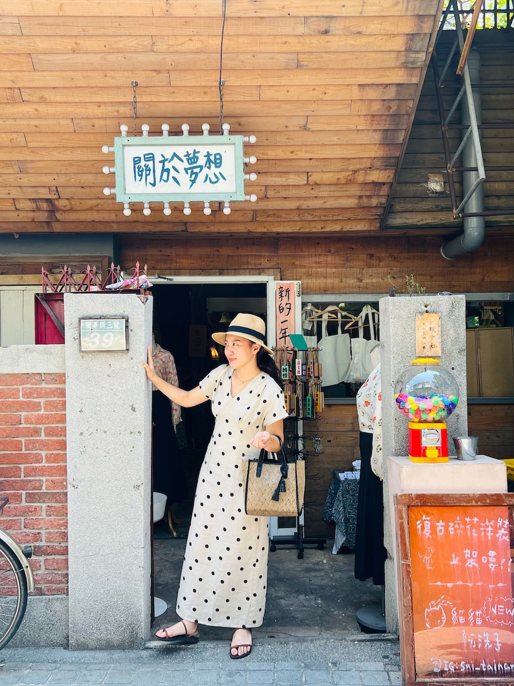 ブラック系のトートバッグ、ベージュ系のワンピース、オレンジ系のサンダルを着用したレディースの夏コーディネートの2枚目の写真