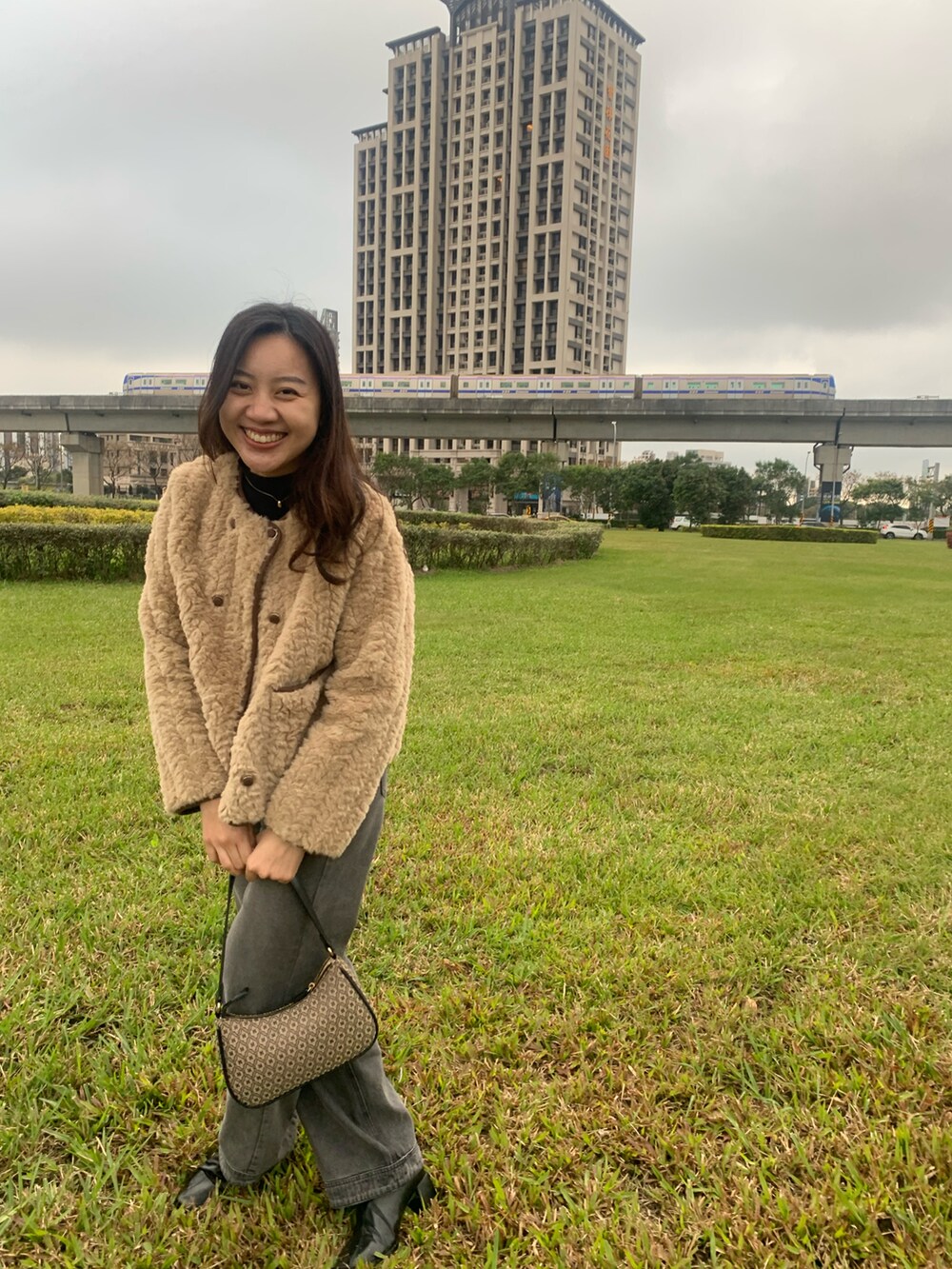 ブラック系のショルダーバッグ、グレー系のデニムパンツを着用したレディースの冬コーディネートの2枚目の写真