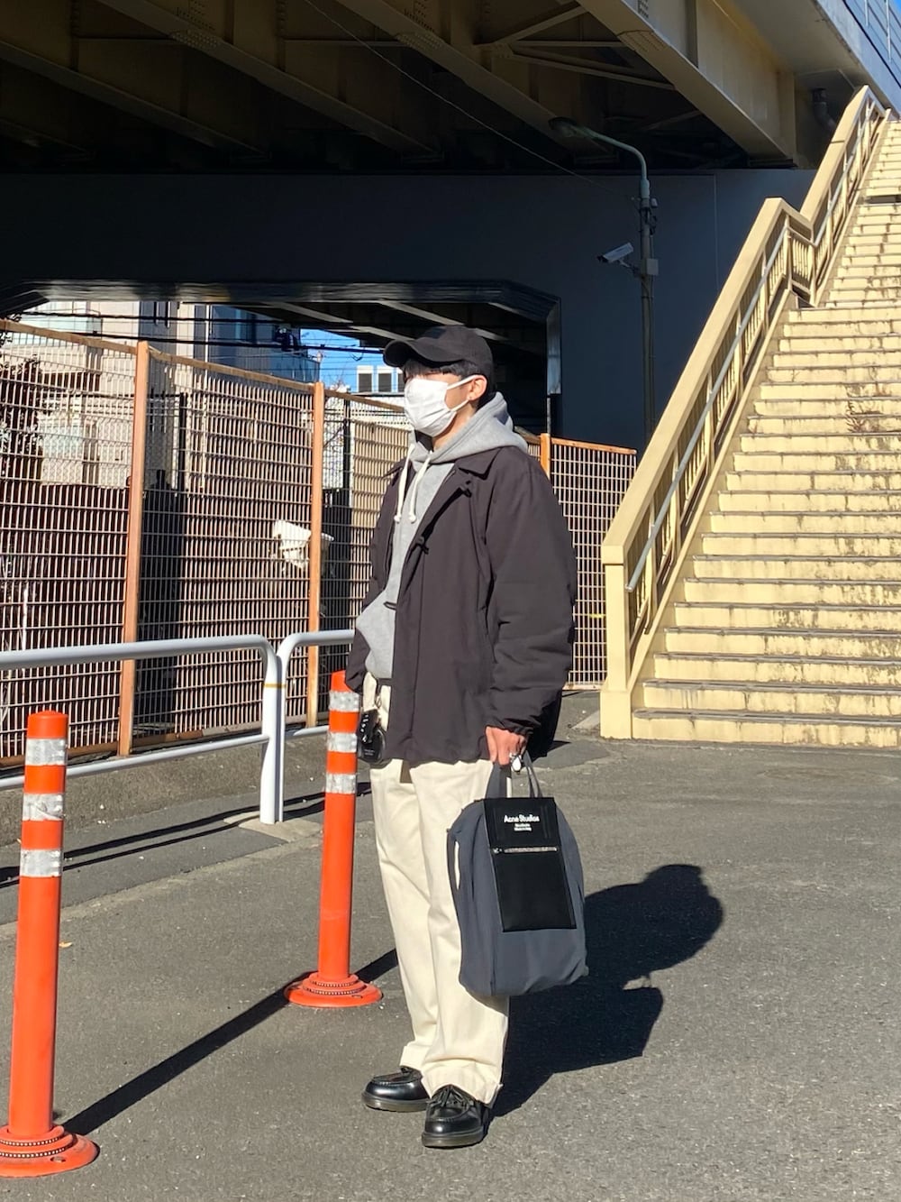 ブラック系のダウンジャケット/コート、グレー系のパーカー、ホワイト系のチノパンツを着用したメンズの冬コーディネートの4枚目の写真