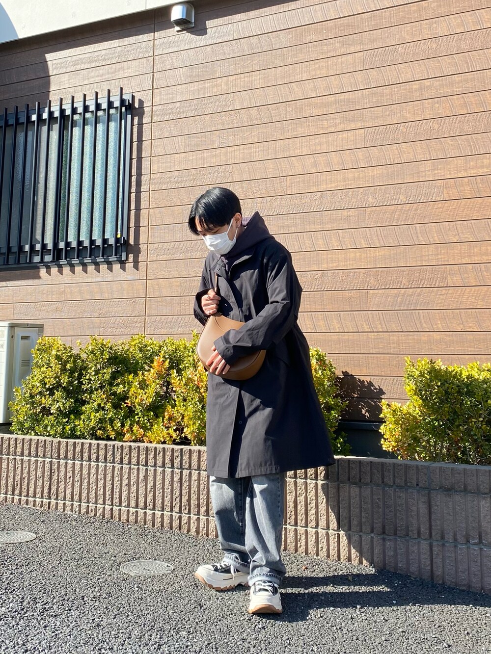 ブラック系のモッズコート、グレー系のパーカー、ブラウン系のバッグを着用したメンズの春コーディネートの5枚目の写真