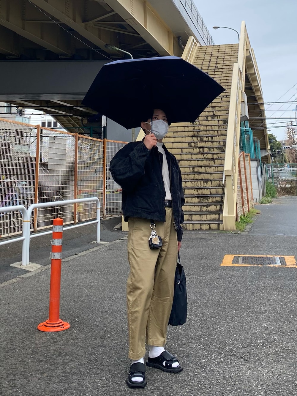 ブラック系のブルゾン、ホワイト系のTシャツ/カットソー、ベージュ系のチノパンツを着用したメンズの春コーディネートの3枚目の写真