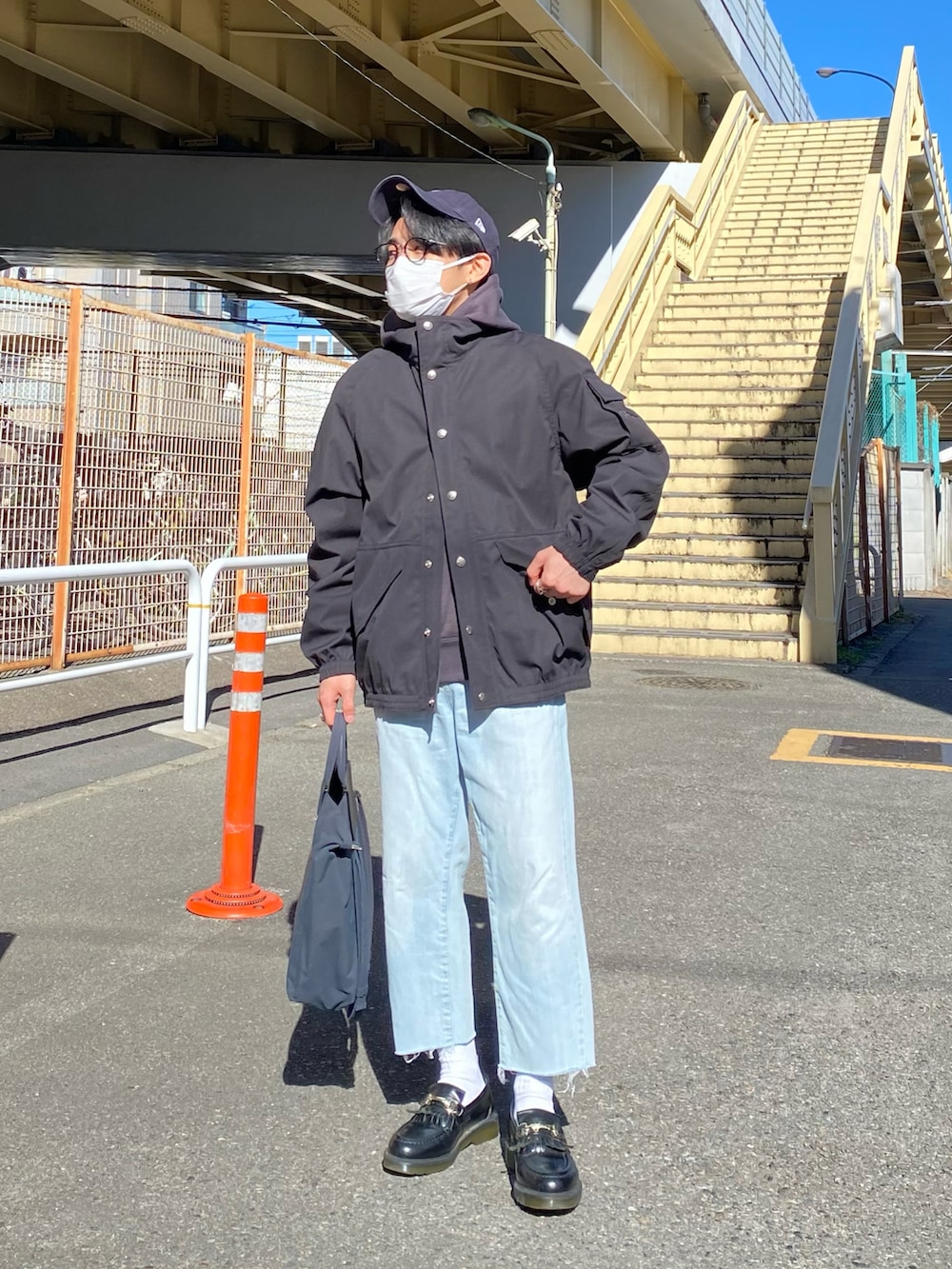 ブラック系のブルゾン、グレー系のパーカー、ブルー系のデニムパンツを着用したメンズの冬コーディネートの2枚目の写真