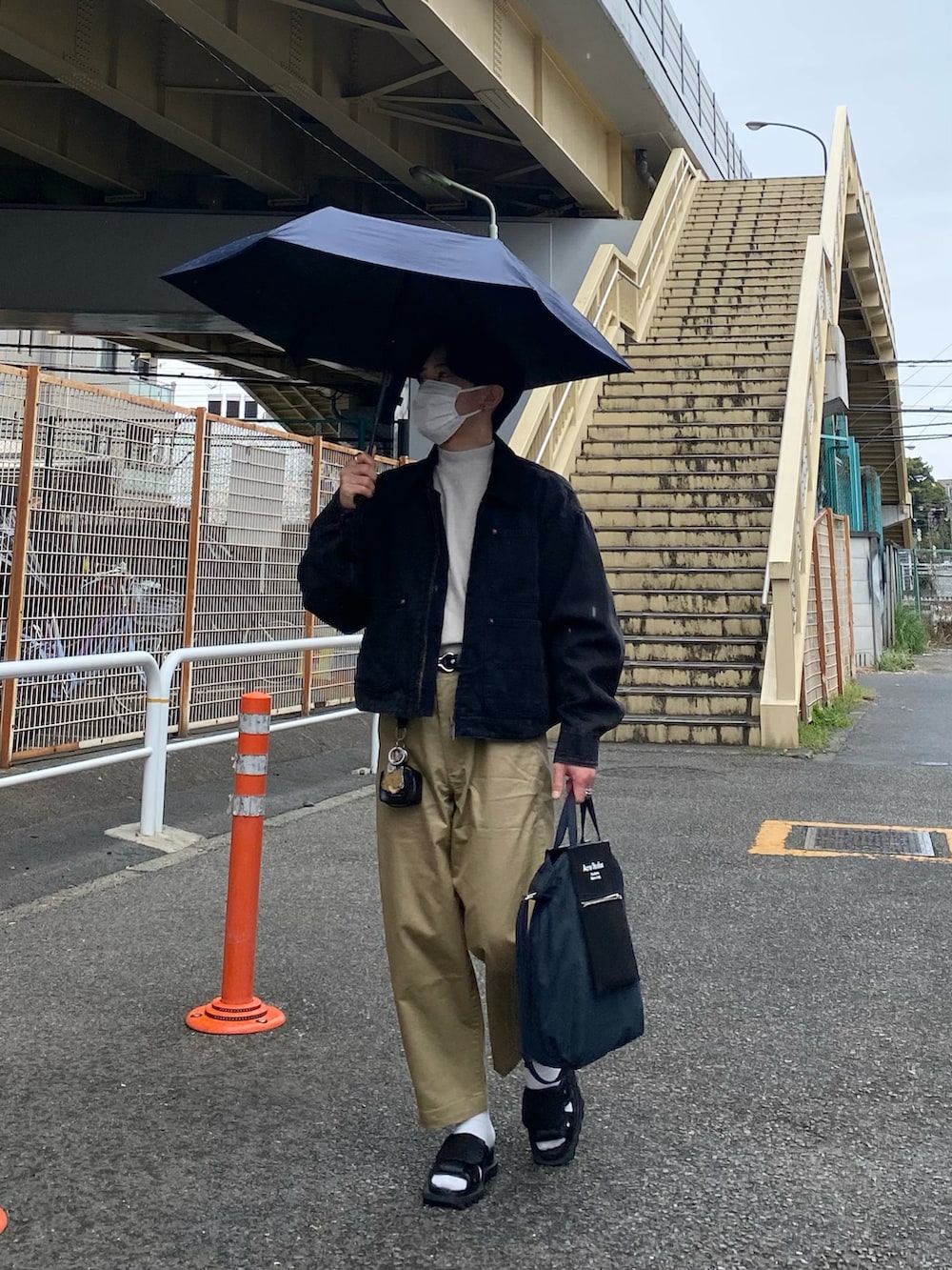 ブラック系のブルゾン、ホワイト系のTシャツ/カットソー、ベージュ系のチノパンツを着用したメンズの春コーディネートの2枚目の写真