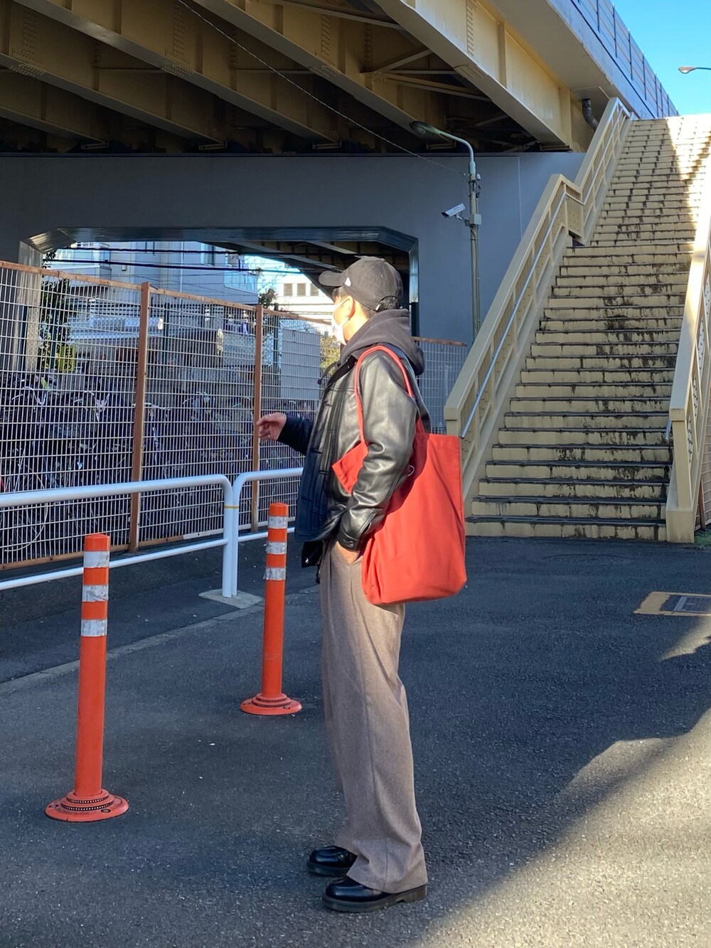 ブラック系のライダースジャケット、ブラック系のパーカー、レッド系のトートバッグを着用したメンズの秋コーディネートの4枚目の写真