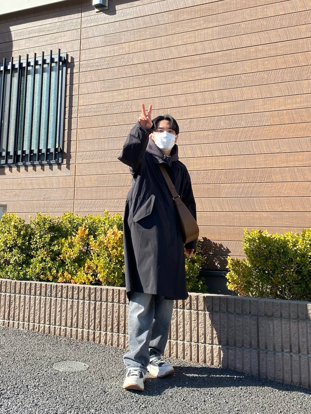 ブラック系のモッズコート、グレー系のパーカー、ブラウン系のバッグを着用したメンズの春コーディネートの4枚目の写真