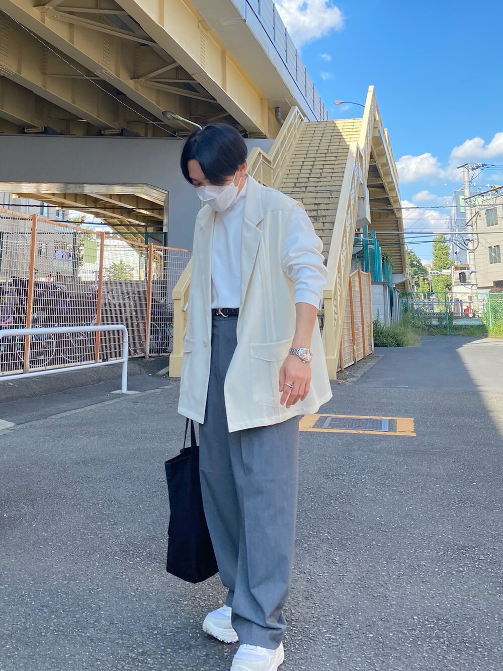 ベージュ系のベスト、グレー系のパンツ、ホワイト系のスニーカーを着用したメンズの秋コーディネートの4枚目の写真