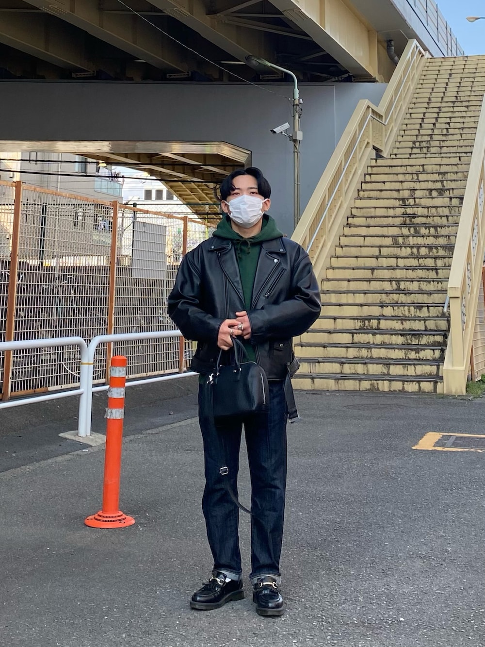 ブラック系のライダースジャケット、グリーン系のパーカー、ブルー系のデニムパンツを着用したメンズの春コーディネートの5枚目の写真