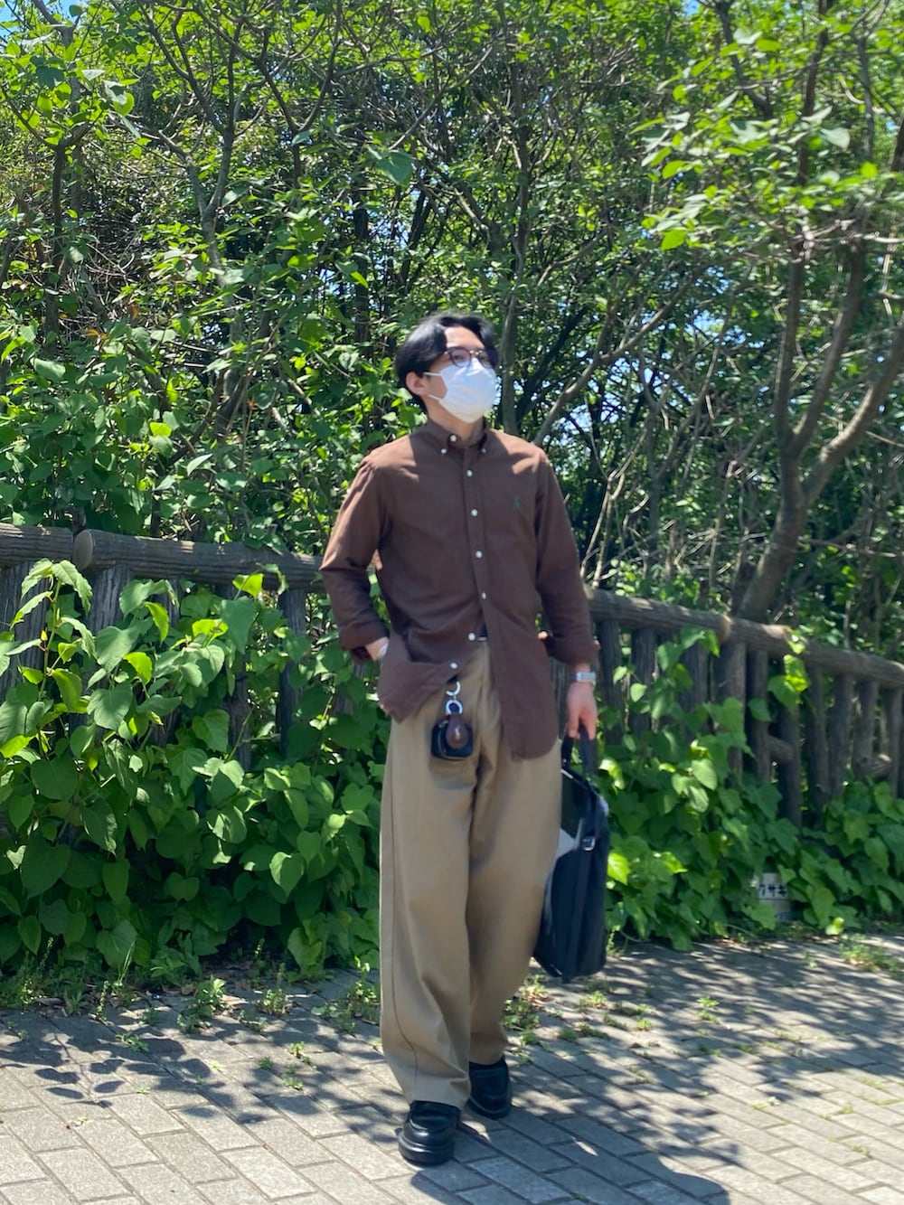 ブラウン系のシャツ/ブラウス、ベージュ系のチノパンツ、ブラック系のトートバッグを着用したメンズの春コーディネートの3枚目の写真