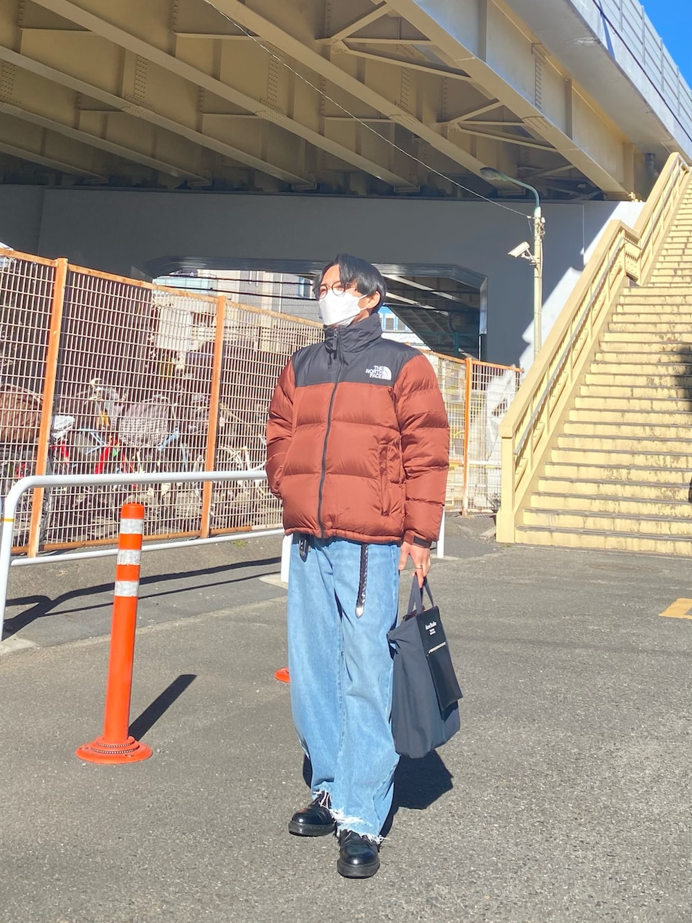 ブラウン系のダウンジャケット/コート、ブラック系のスウェット、ブルー系のデニムパンツを着用したメンズの冬コーディネートの2枚目の写真