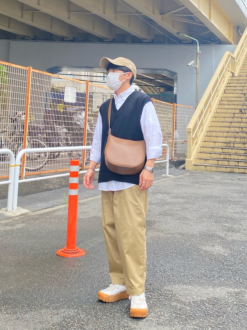 ブラック系のベスト、ホワイト系のシャツ/ブラウス、ベージュ系のチノパンツを着用したメンズの秋コーディネートの2枚目の写真