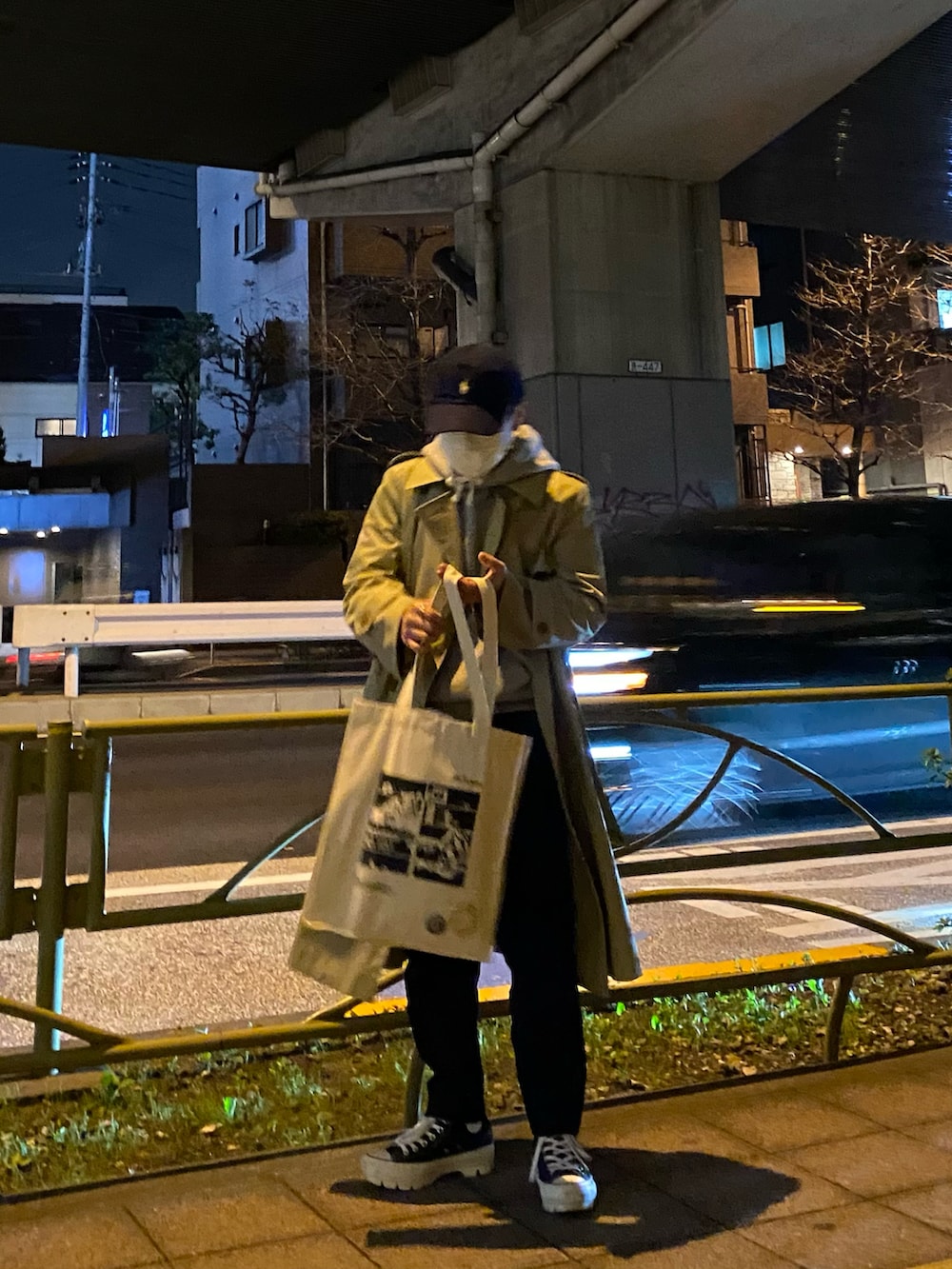 ベージュ系のトレンチコート、グレー系のパーカー、ホワイト系のトートバッグを着用したメンズの春コーディネートの3枚目の写真