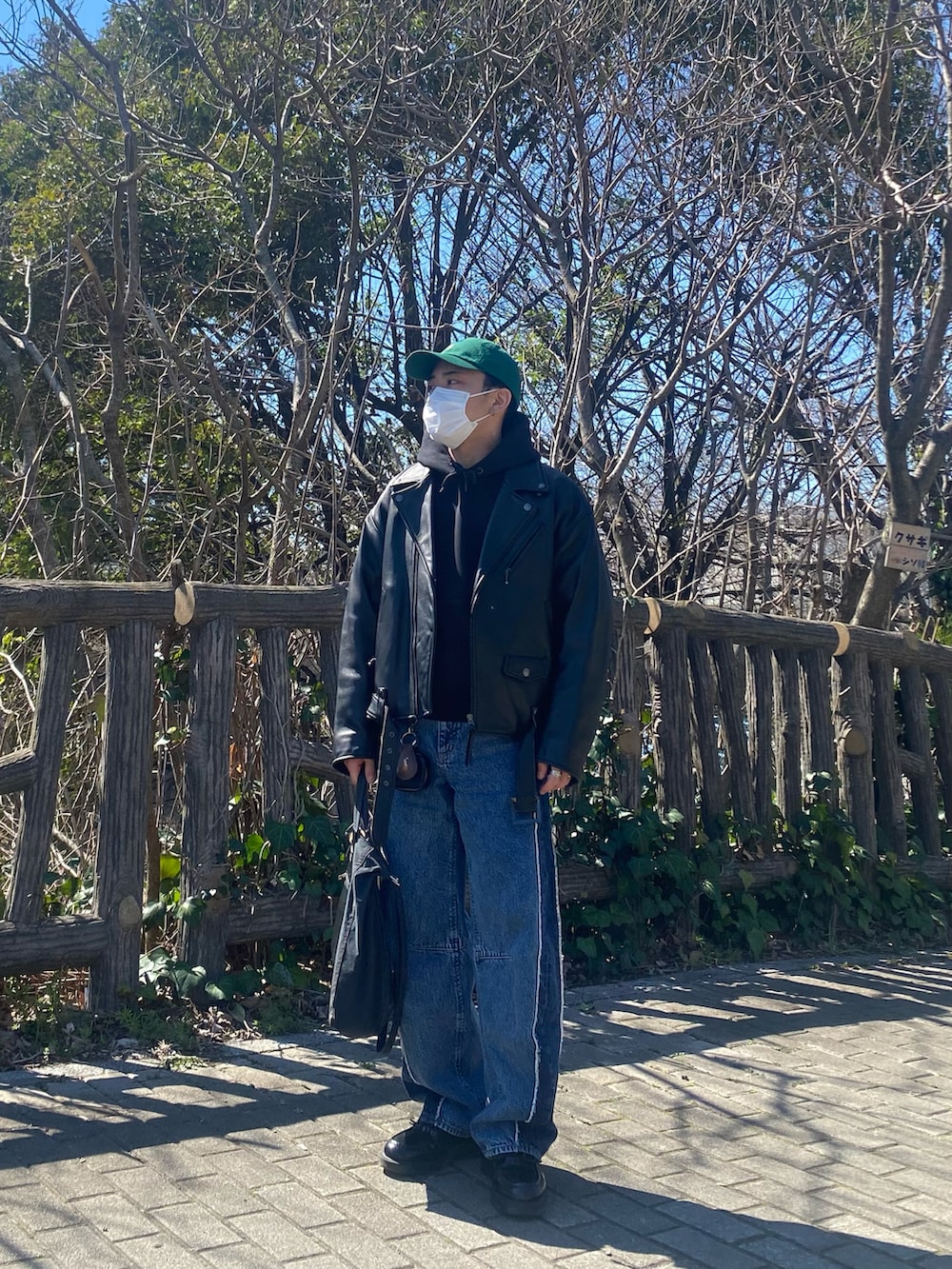 ブラック系のライダースジャケット、ブラック系のパーカー、ブルー系のデニムパンツを着用したメンズの春コーディネートの2枚目の写真