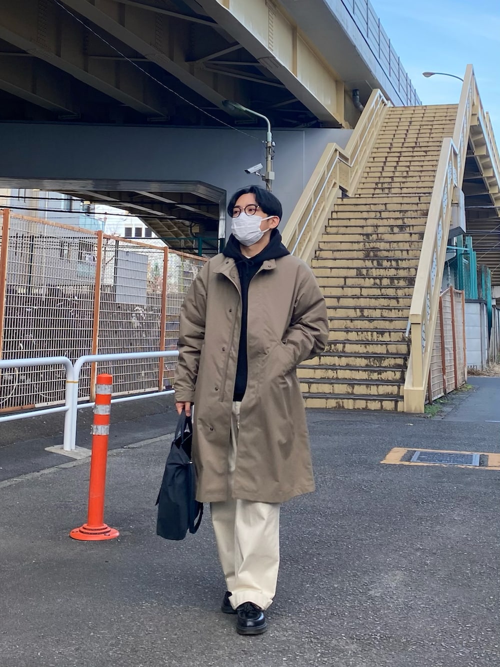 ブラウン系のモッズコート、ブラック系のパーカー、ホワイト系のチノパンツを着用したメンズの冬コーディネートの2枚目の写真