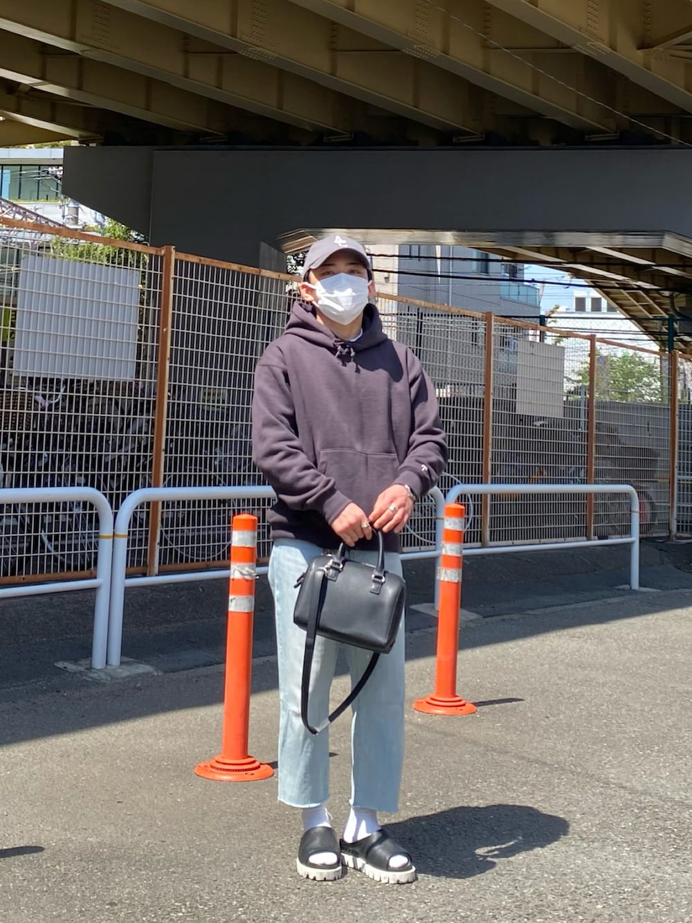 グレー系のパーカー、ブルー系のデニムパンツ、ブラック系のサンダルを着用したメンズの春コーディネートの2枚目の写真