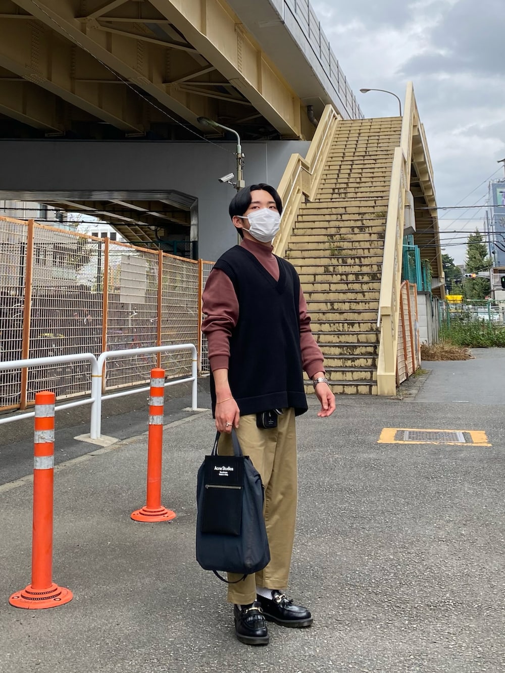 ブラック系のベスト、レッド系のTシャツ/カットソー、ベージュ系のチノパンツを着用したメンズの秋コーディネートの2枚目の写真