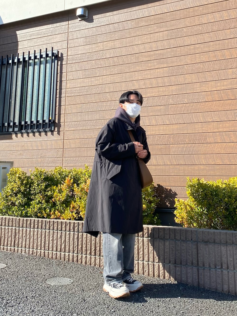 ブラック系のモッズコート、グレー系のパーカー、ブラウン系のバッグを着用したメンズの春コーディネートの3枚目の写真