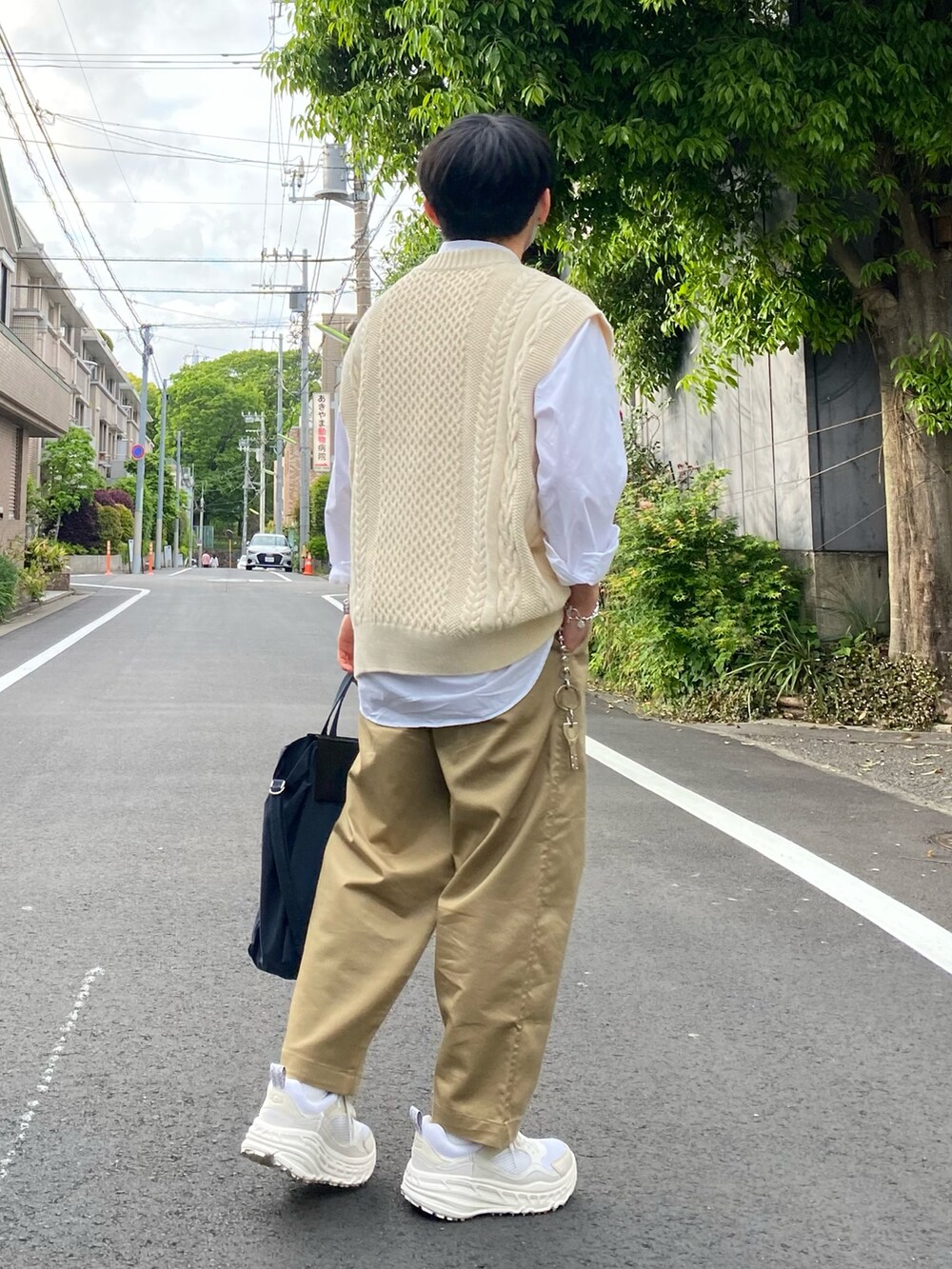 ベージュ系のニット/セーター、ホワイト系のシャツ/ブラウス、ブラック系のトートバッグを着用したメンズの春コーディネートの4枚目の写真