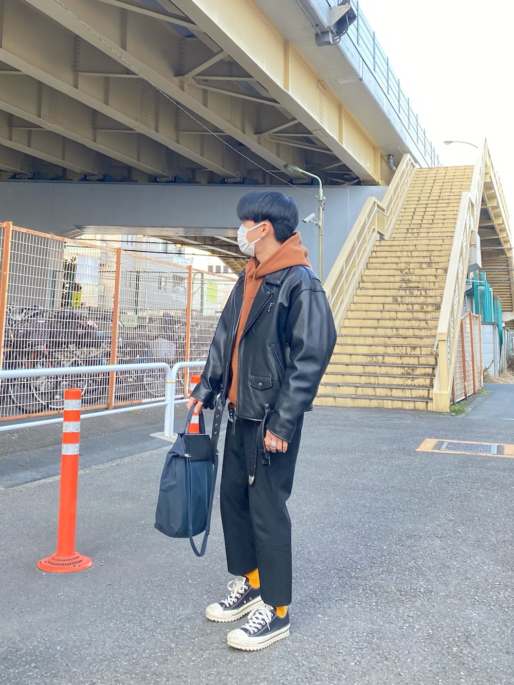 ブラック系のライダースジャケット、ブラウン系のパーカー、ブラック系のスラックスを着用したメンズの冬コーディネートの4枚目の写真