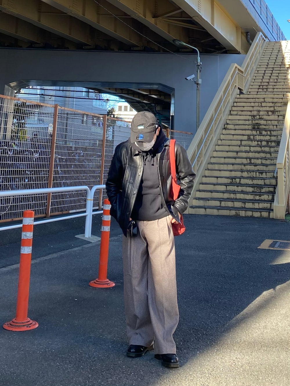 ブラック系のライダースジャケット、ブラック系のパーカー、レッド系のトートバッグを着用したメンズの秋コーディネートの2枚目の写真