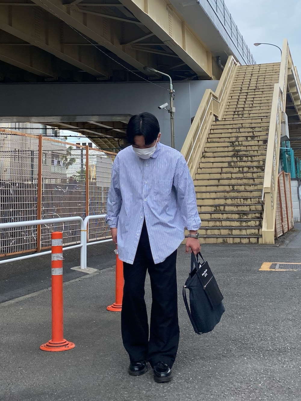 ブルー系のシャツ/ブラウス、ブラック系のトートバッグ、ブラック系のパンツを着用したメンズの春コーディネートの2枚目の写真