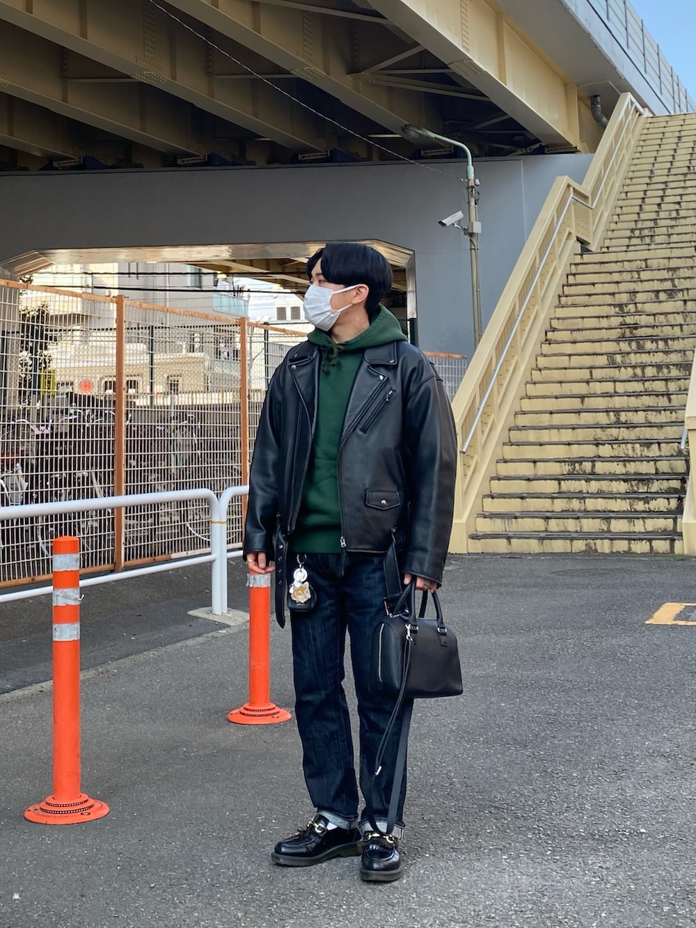 ブラック系のライダースジャケット、グリーン系のパーカー、ブルー系のデニムパンツを着用したメンズの春コーディネートの2枚目の写真