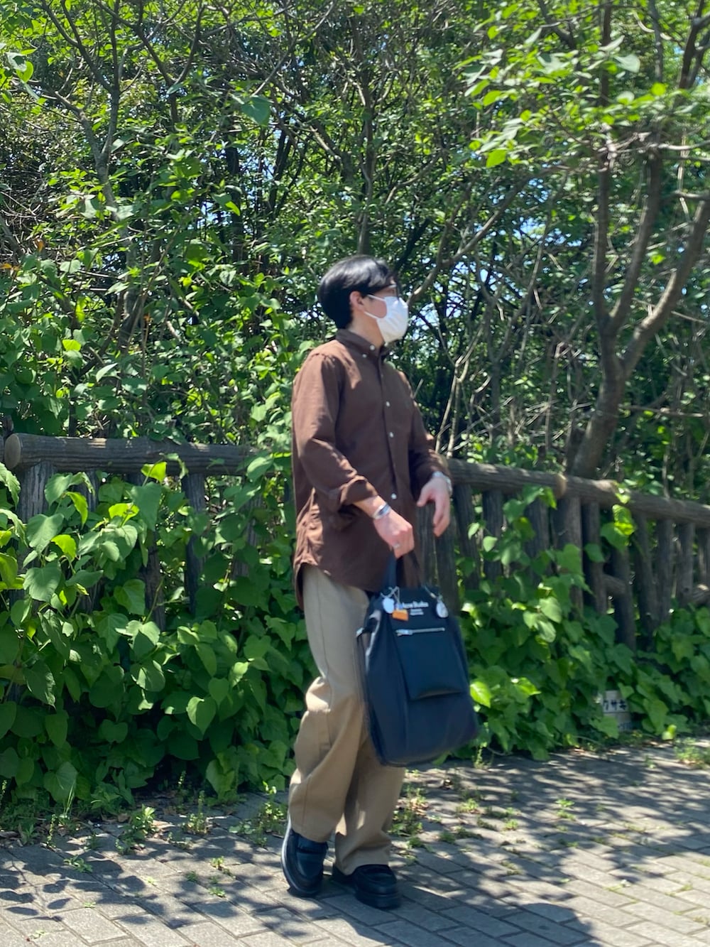 ブラウン系のシャツ/ブラウス、ベージュ系のチノパンツ、ブラック系のトートバッグを着用したメンズの春コーディネートの4枚目の写真