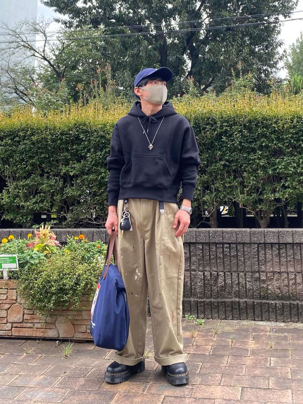 ベージュ系のチノパンツ、ブラック系のブーツ、ブルー系のトートバッグを着用したメンズの秋コーディネートの2枚目の写真