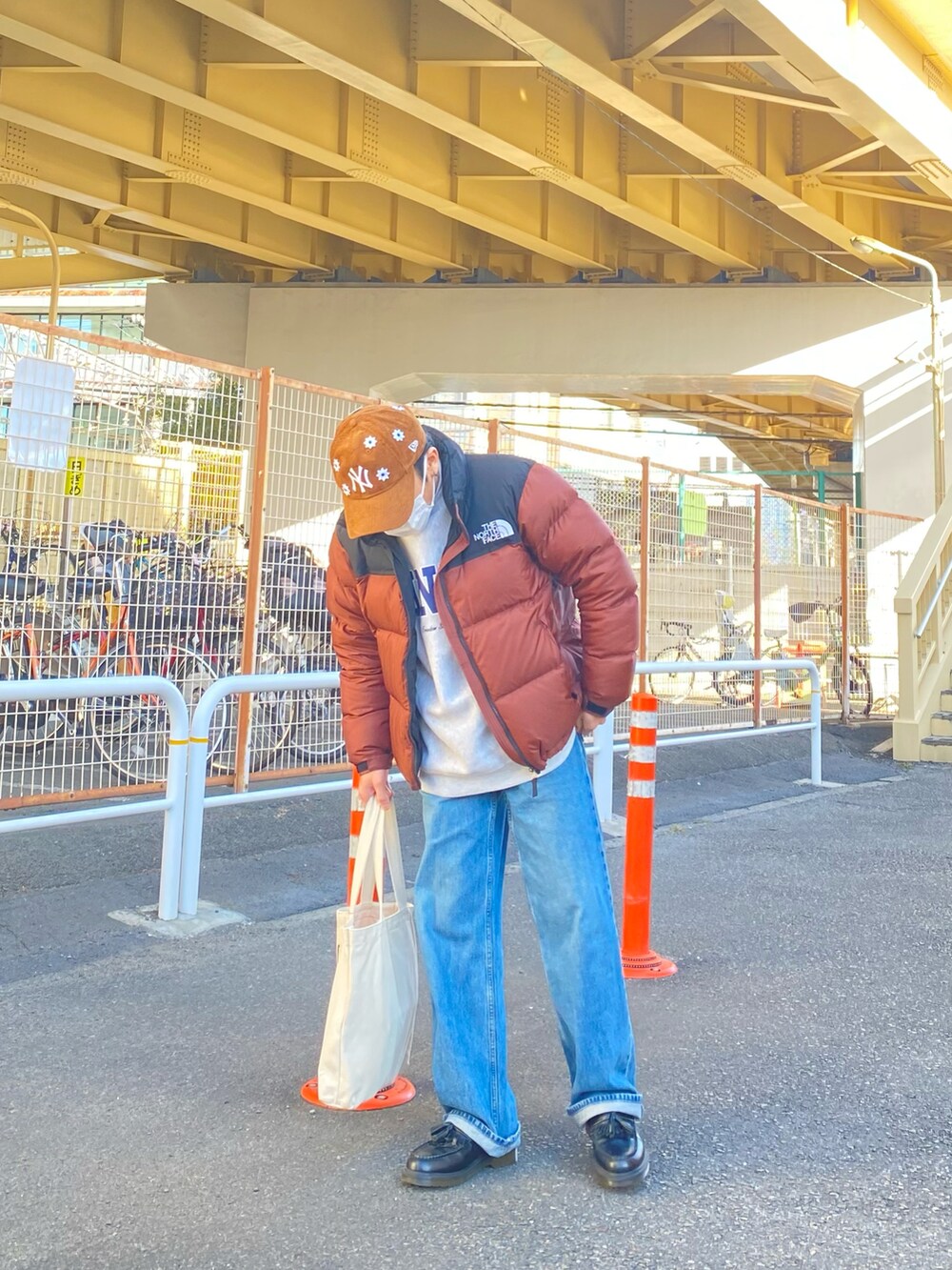 ブラウン系のダウンジャケット/コート、グレー系のスウェット、ブルー系のデニムパンツを着用したメンズの冬コーディネートの2枚目の写真