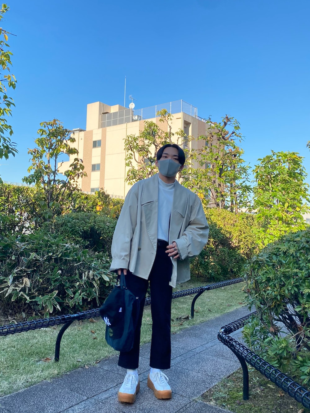 ベージュ系のトレンチコート、ブラック系のカーディガン/ボレロ、ホワイト系のTシャツ/カットソーを着用したメンズの秋コーディネートの3枚目の写真