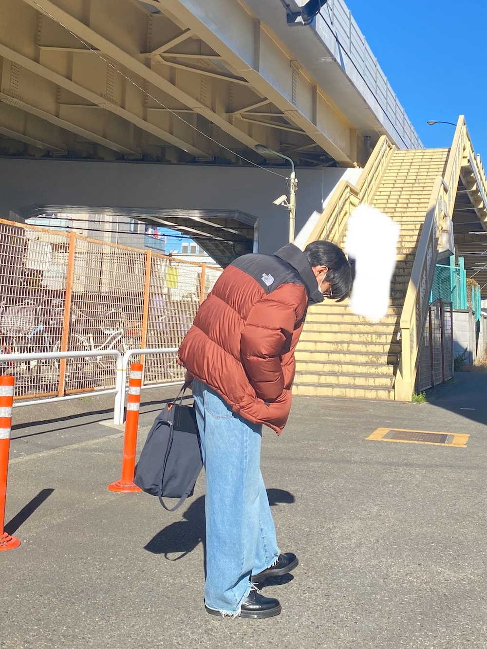 ブラウン系のダウンジャケット/コート、ブラック系のスウェット、ブルー系のデニムパンツを着用したメンズの冬コーディネートの4枚目の写真